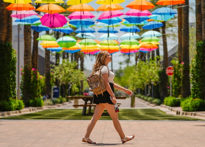 Julia Vorbeck, 16, walks by an umbrella art installation at Tempe Marketplace in July 2022.
