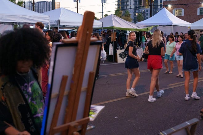 Shyla Ferrell paints as people walk past during the First Friday art walk on Aug. 4, 2023, in downtown Phoenix.