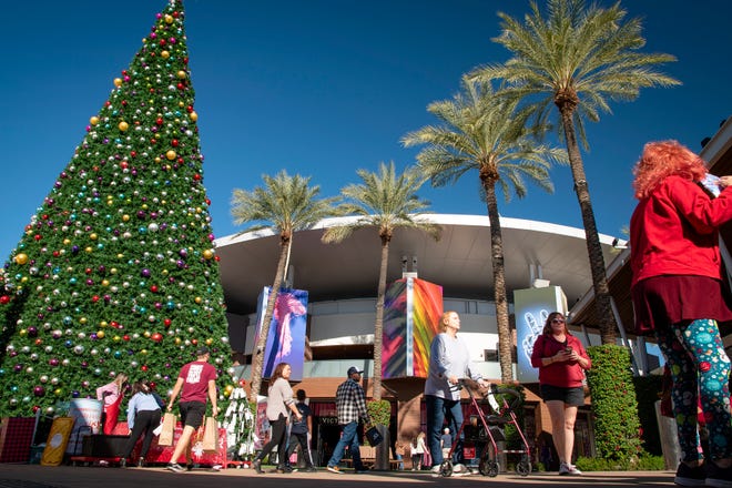 A crowd of Black Friday shoppers walks past a towering Christmas tree at Tempe Marketplace in 2021.